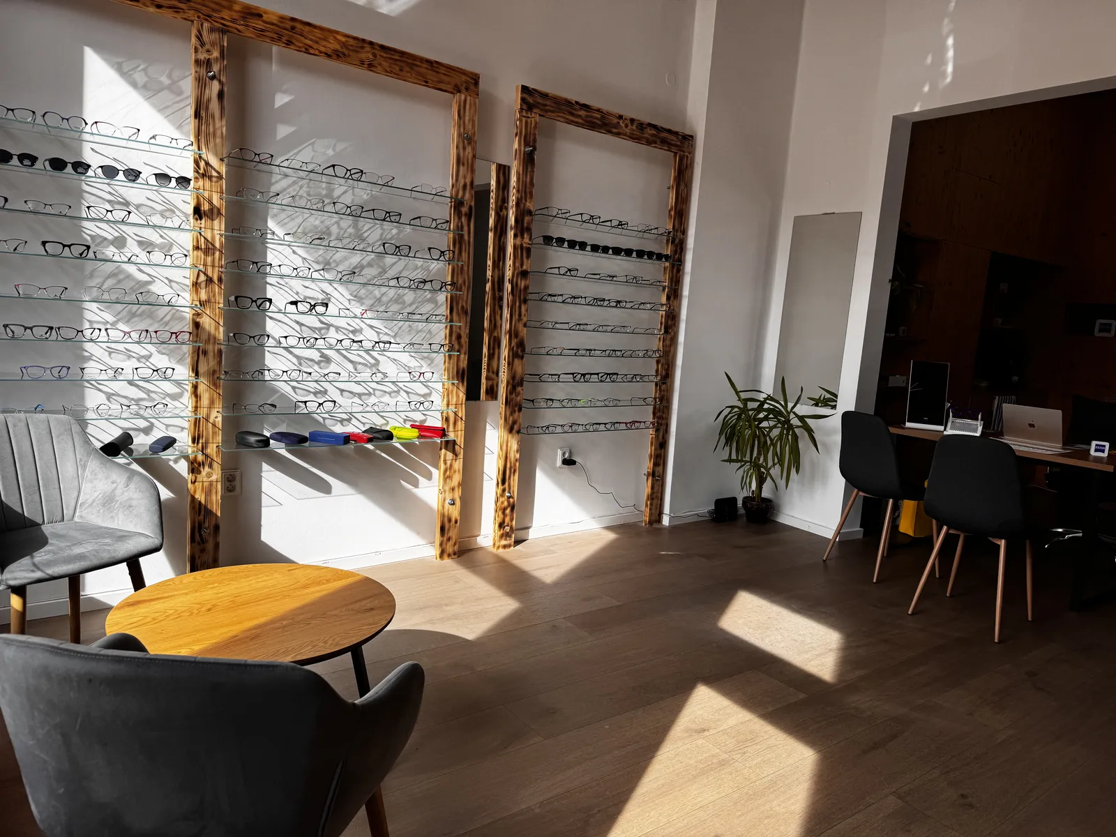Interiér optiky Medi Optik v Heřmanově Městci – stěna s obrubami a posezení